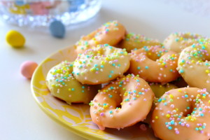Multi coloured ring cookies on a yellow plate.