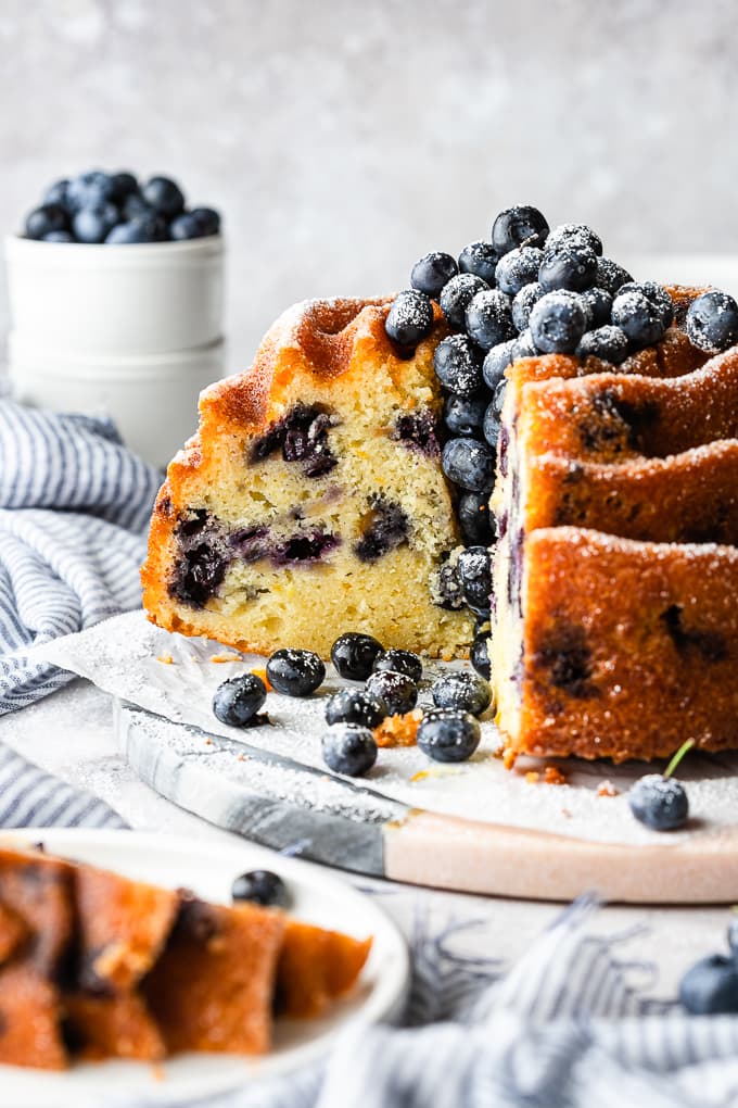 A blueberry and orange cake with three slices cut off.