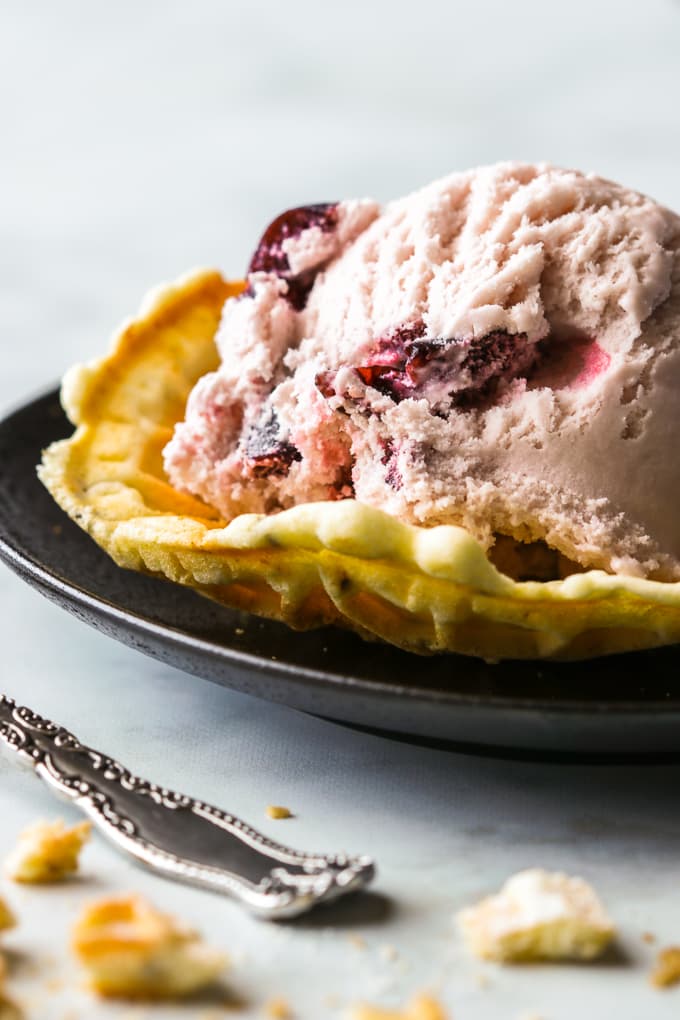 Classic pizzelle cookie shaped into a bowl and topped with black cherry ice cream.