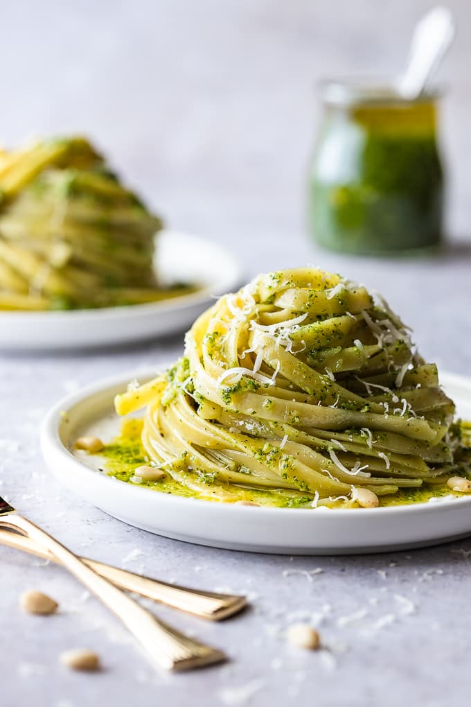 Fettuccine pasta tossed with basil pesto on a white plate.
