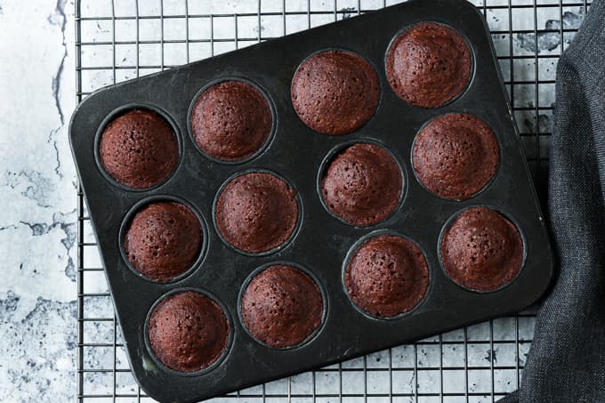 Freshly baked mini brownies in grey baking tins.