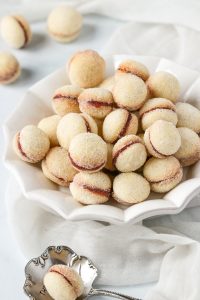 A white cookie platter filled with butterball cookies.