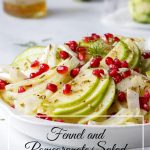 White bowl with fennel, sliced apples and pomegranate arils.