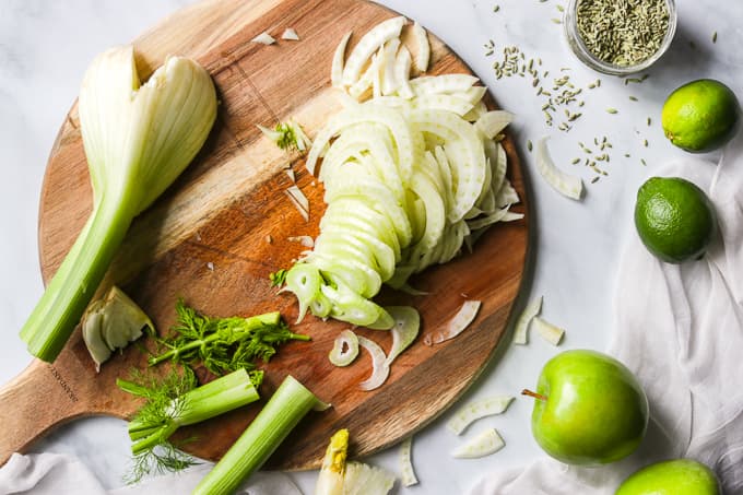 Thin slices of fennel on a cutting board.