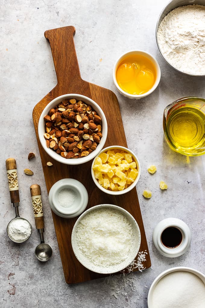 A wooden board filled with bowls for ingredients to make almond biscotti.