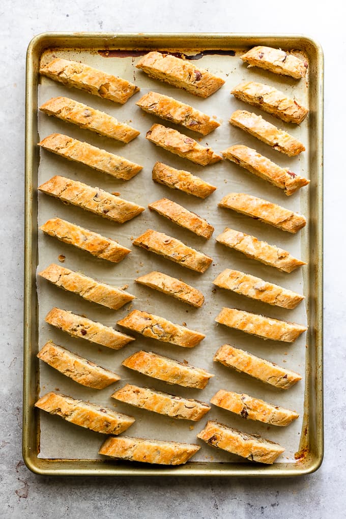 Sliced almond biscotti on a parchment lined baking sheet.