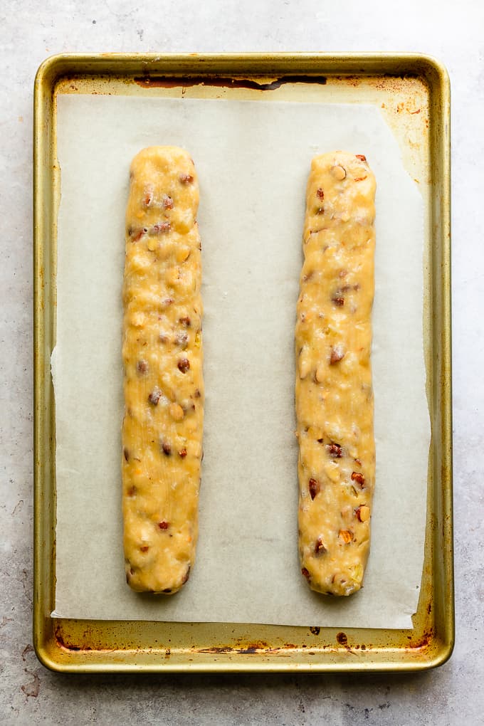 Almond biscotti logs on a parchment lined baking sheet.