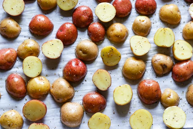 Sliced red and golden potatoes on a baking sheet.