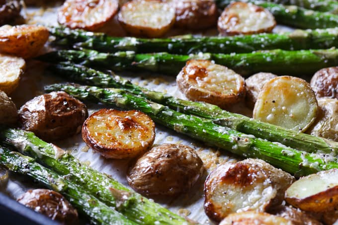 Roasted baby potatoes and asparagus on a baking sheet.