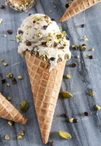 An ice cream cone filled with two scoops of pistachio gelato