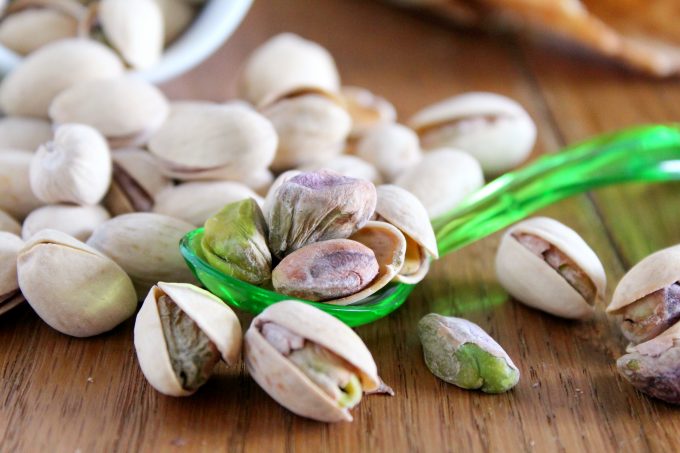 Pistachios with their shell on placed on a wooden board.