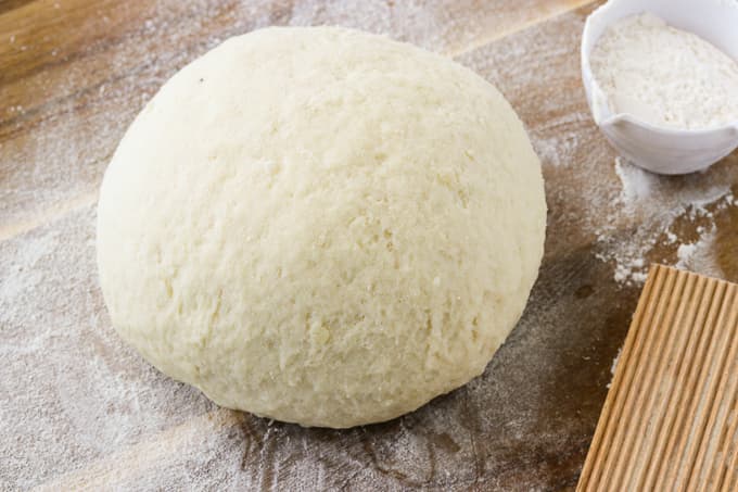 Gnocchi dough on a wooden board.