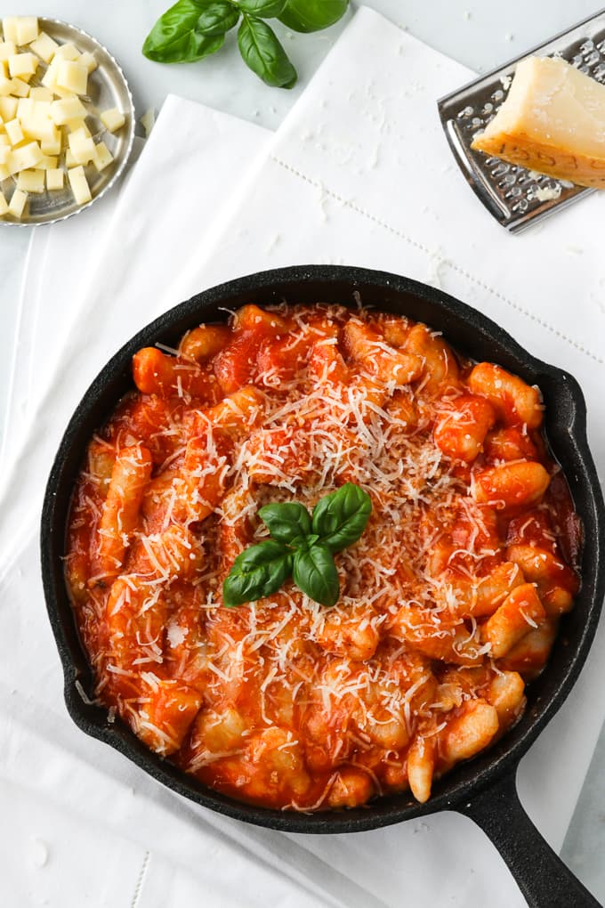 Potato gnocchi with tomato sauce in a black skillet.