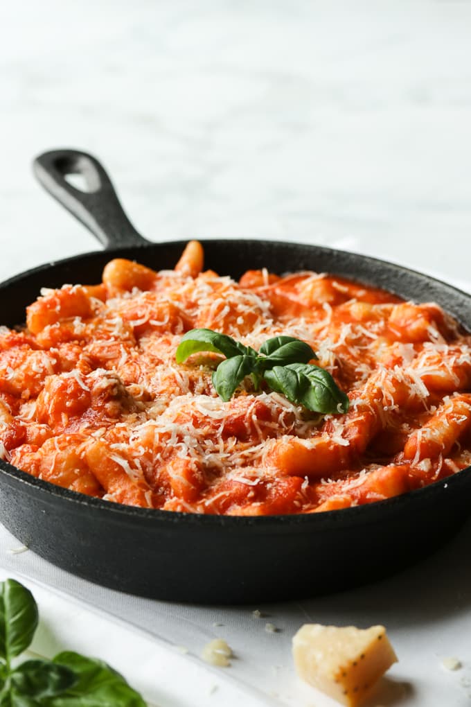 Gnocchi in a skillet topped with Parmesan cheese