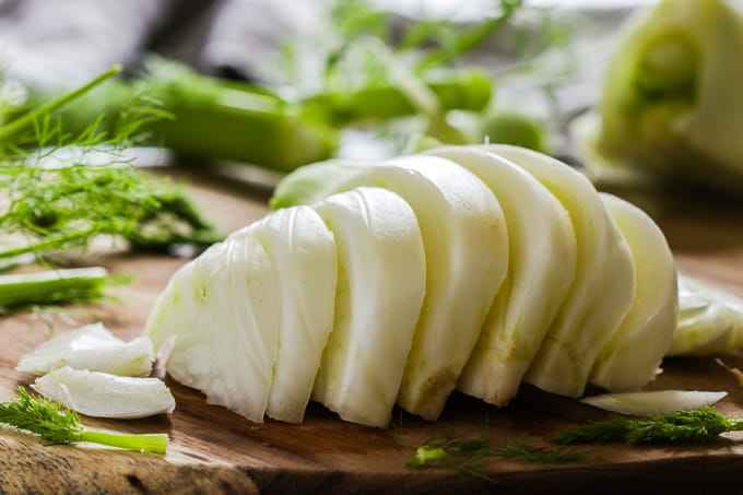 Sliced fennel on a wooden cutting board.