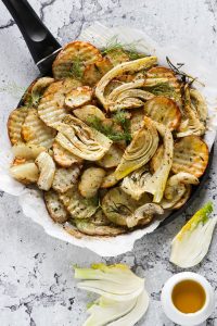 Oven roasted vegetables on a black pan.