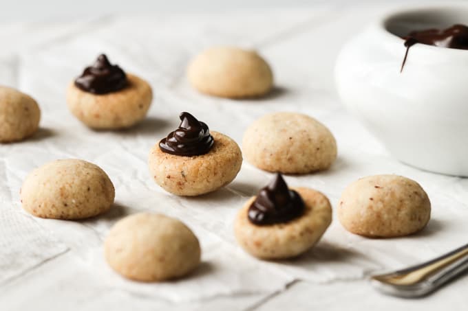 Piping dark chocolate onto hazelnut cookies.