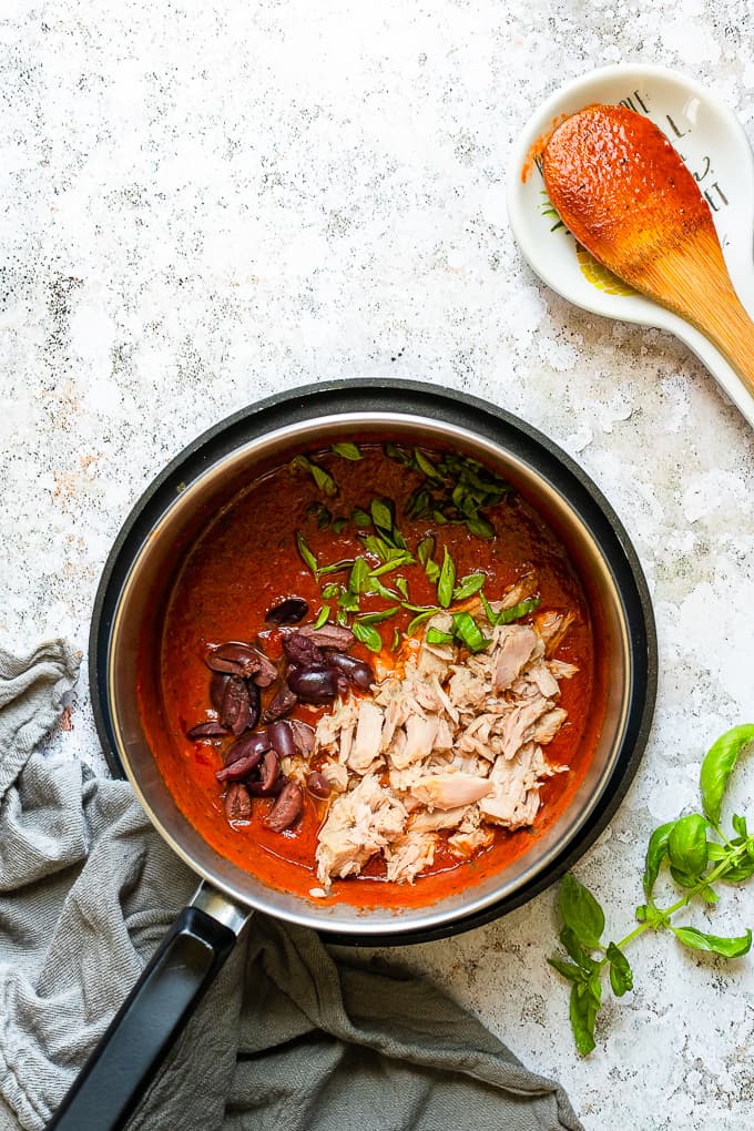 A sauce pot with tomato, basil and tuna sauce.