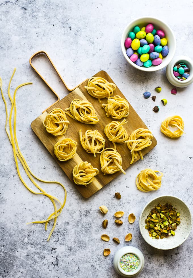Fresh pasta twirled into nests on a wooden board.