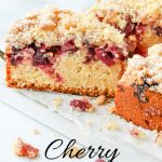 Sliced Cherry Crumb Cake on a white wooden board.