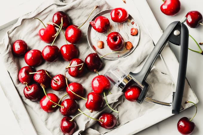 Pitted cherries on a white wooden board.