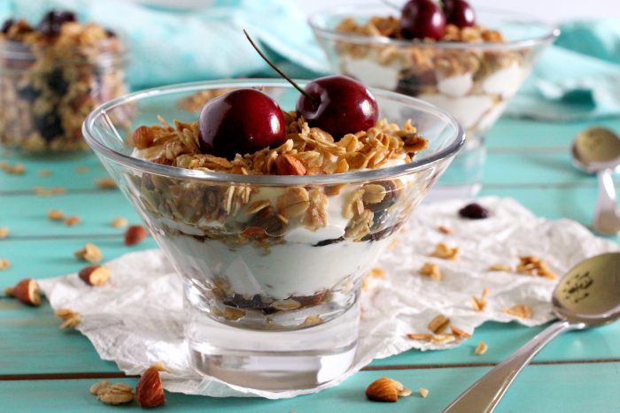 Small parfait glasses filled with cherry granola and yoghurt mixture.