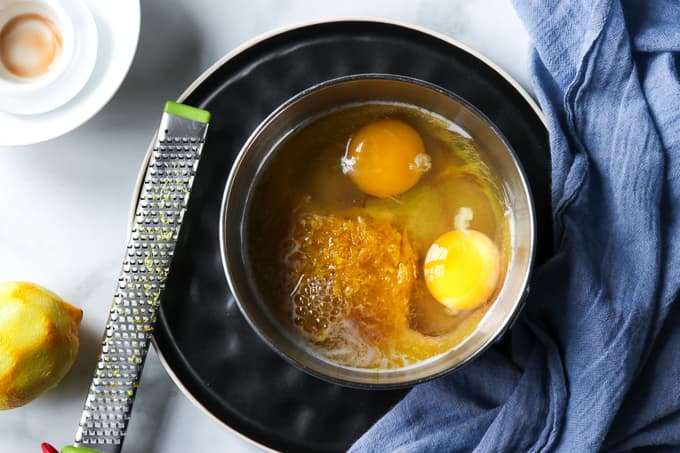 A small silver bowl with 2 eggs, lemon peel, sugar and vanilla extract.