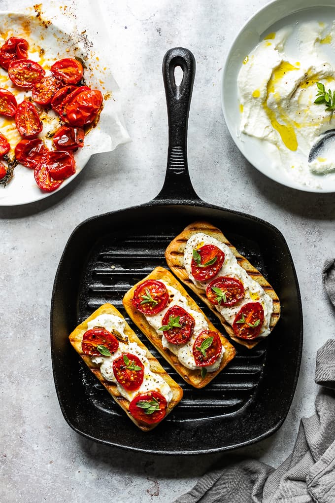 Bruschetta with roasted tomatoes and whipped ricotta on a grill pan.