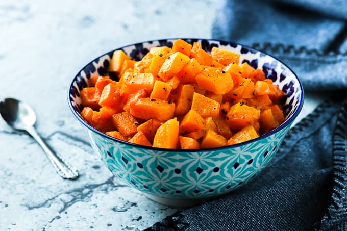 A blue and white bowl filled with diced and roasted butternut squash.
