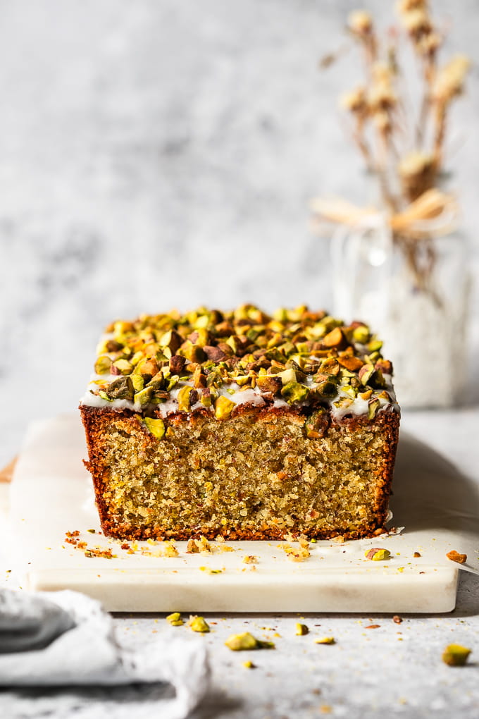 Sliced almond pistachio cake on a marble board.