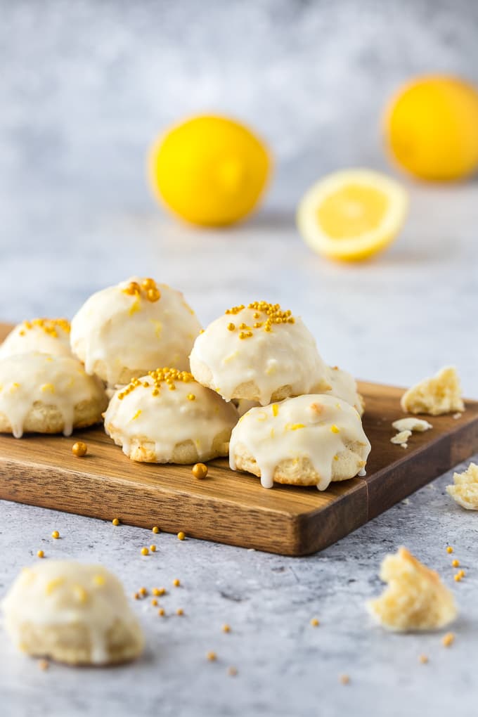 Italian lemon ricotta cookies on a wooden board with 2 glasses of milk in the background.