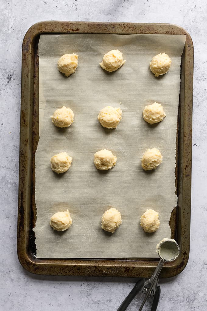 A prey metal sheet pan with scoops of ricotta cookies placed 2 inches apart.