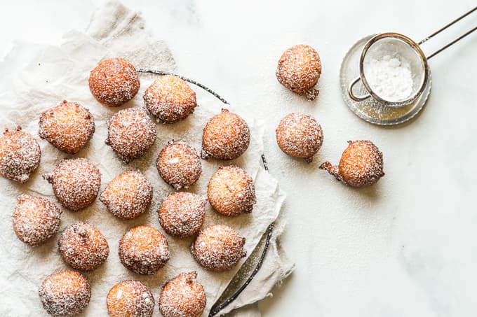 Dusting powdered sugar over the fried zeppole.