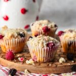 Raspberry and blackberry muffins on a wooden board.