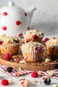 Raspberry and blackberry muffins on a wooden board.