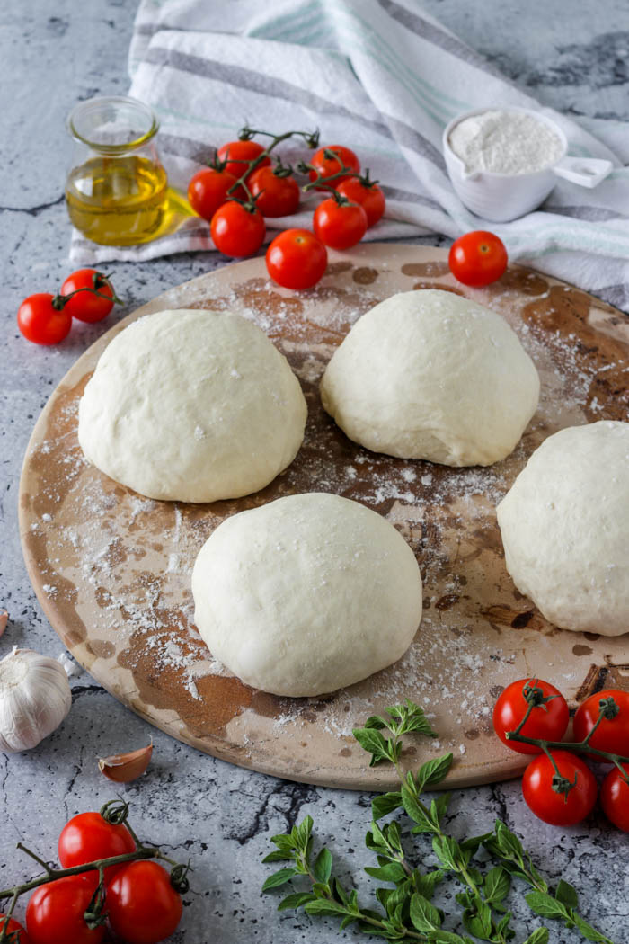 Four balls of focaccia dough on a pizza plate