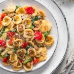 Orecchiette with sausage and rapini on a white serving plate.