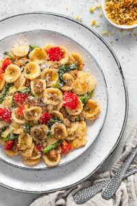 Orecchiette with sausage and rapini on a white serving plate.