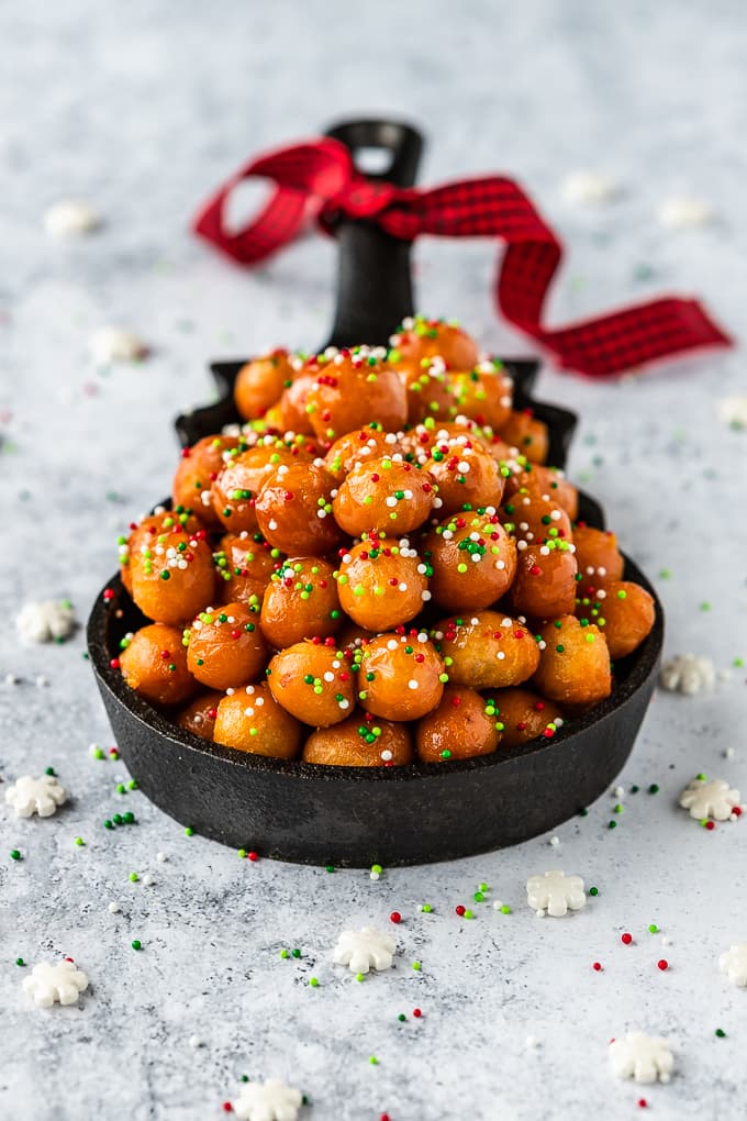 Struffoli served in a cast iron skillet and topped with sprinkles.