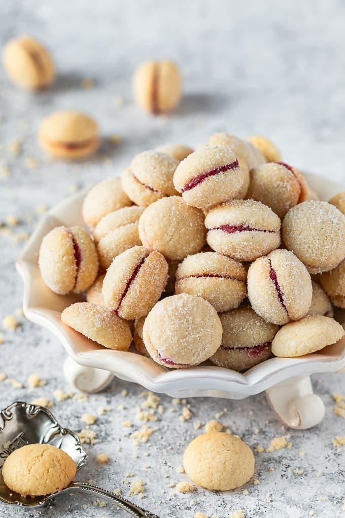 Jam-filled butterball cookies on a white tray.