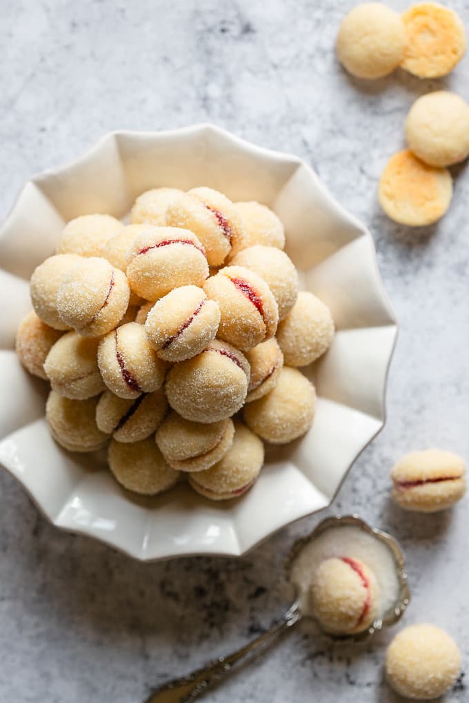 Butterball cookies filled with raspberry jam on a white plate.