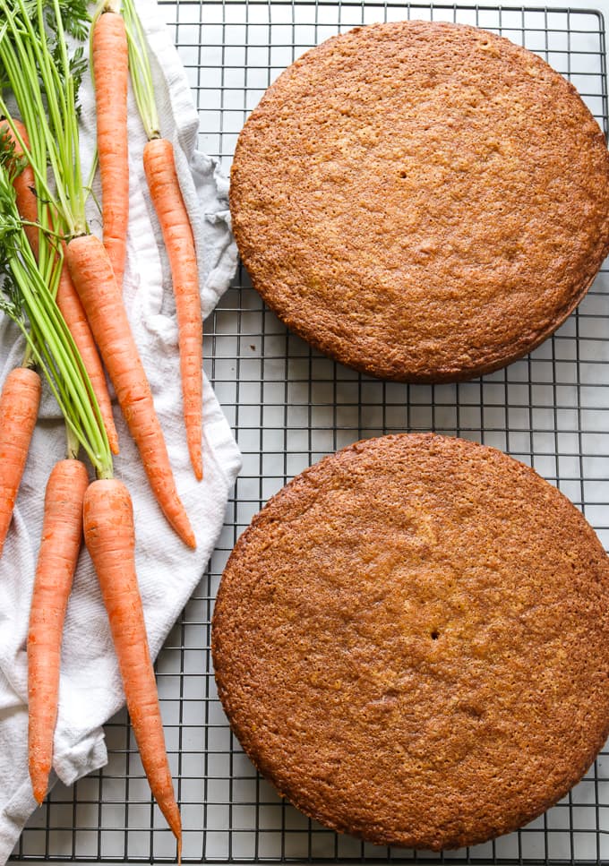 Two layers of carrot cake on a black cooling rack.