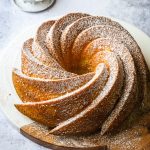 An Italian lemon cake baked in a bundt pan and dusted with powdered sugar on a wooden board.