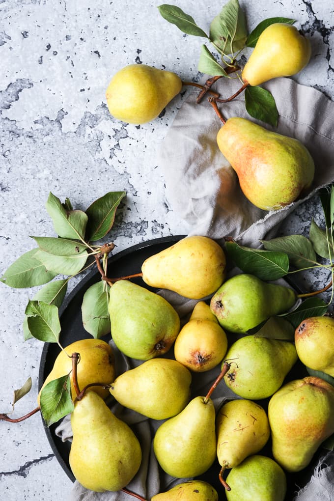 Fresh ripe pears on a black serving tray.