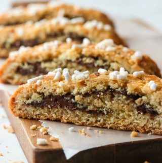 Four slices of Nutella and hazelnut rolled biscotti on a wooden board.