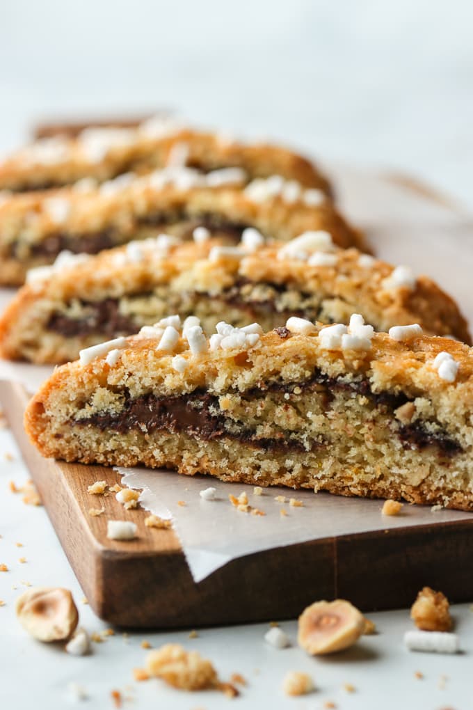 Four slices of Nutella and hazelnut rolled biscotti on a wooden board.