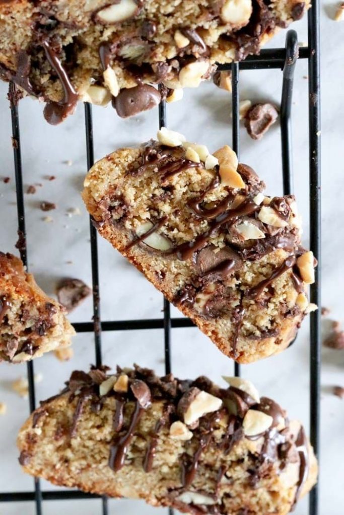 Peanut butter biscotti drizzled with chocolate on a black cooling rack