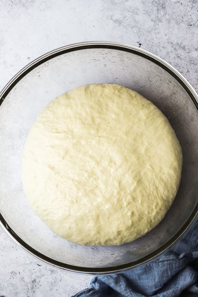 Focaccia bread dough in a greased glass bowl.