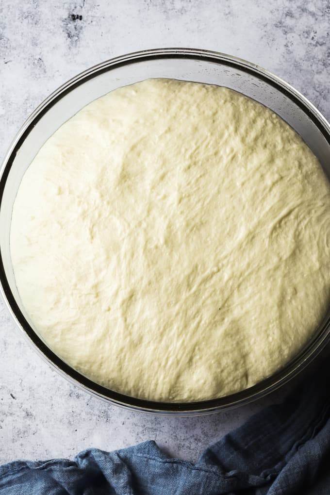 Italian focaccia dough in a glass bowl doubled in size.