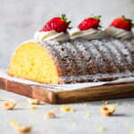 Polenta cake with a slice cut off and topped with strawberries.